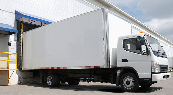 Witte bestelwagen die voor een gebouw staat om geladen te worden