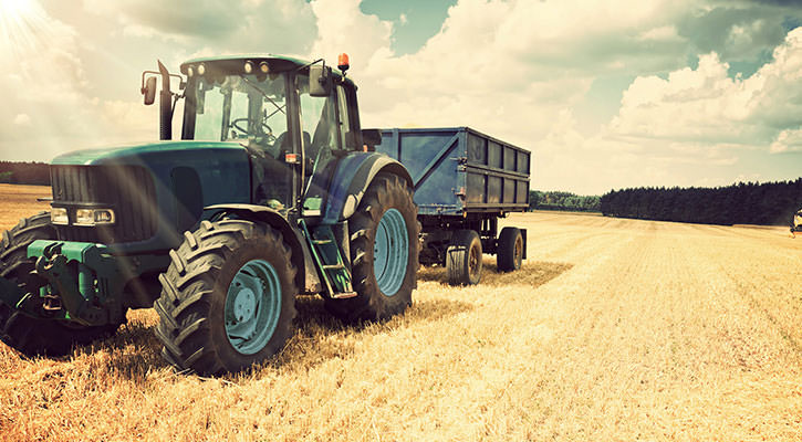 Blauwe trekker met een aanhanger staande op een veld