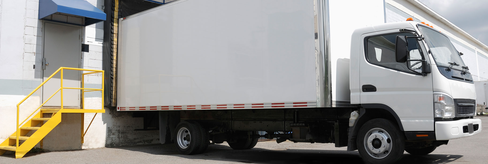 Witte bestelwagen die voor een gebouw staat om geladen te worden