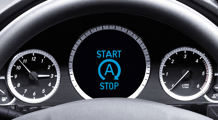 The dashboard of a car with the clock on the left side, the speed indicator on the right side and a start stop sign in the middle